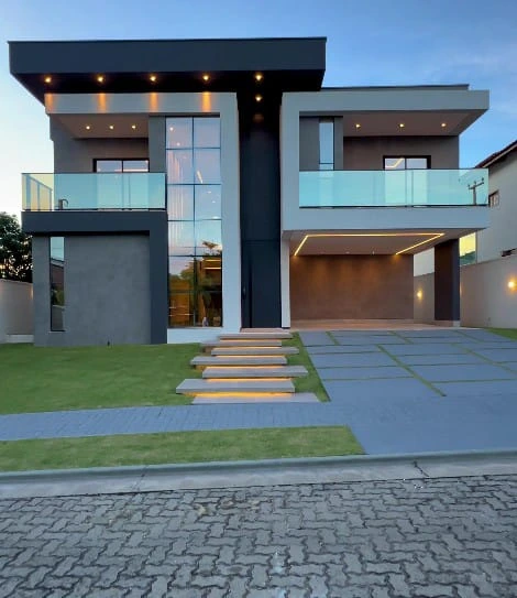 Construcción de vivienda unifamiliar con fachada moderna en tonos grises y grandes ventanales de cristal.