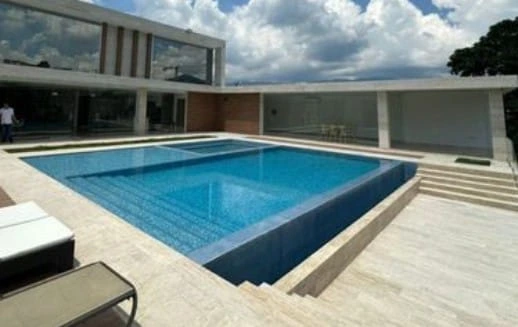 Construcción de piscina desbordante con revestimiento azul y terraza de piedra clara en Madrid