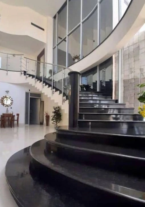 Reforma vivienda con escalera de mármol negro, barandilla de cristal y grandes ventanales en Madrid